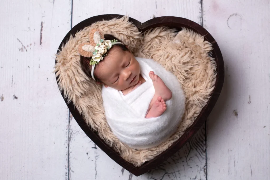 Sleeping newborn baby in heart-shaped basket
